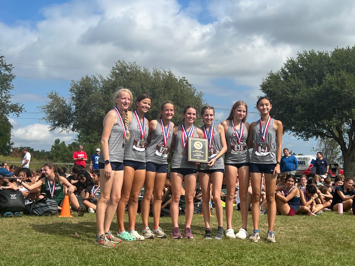 The Tompkins girls cross country team celebrates winning the District 19-6A cross country meet on Thursday morning at Paul D. Rushing Park.